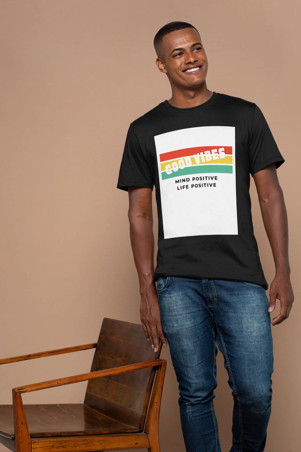 Man wearing a black t-shirt with a colorful graphic design and text Good Vibes Mind Positive Life Positive in a beige background