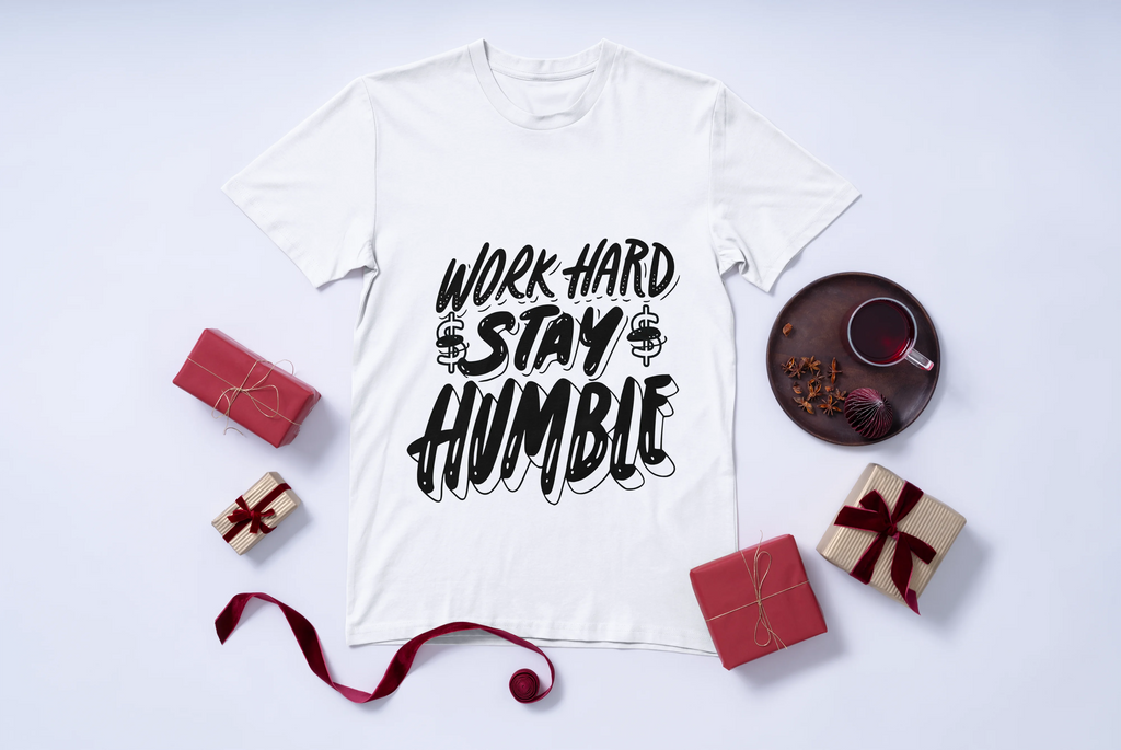 White t-shirt with 'Work Hard Stay Humble' text on a white background with decorative items.