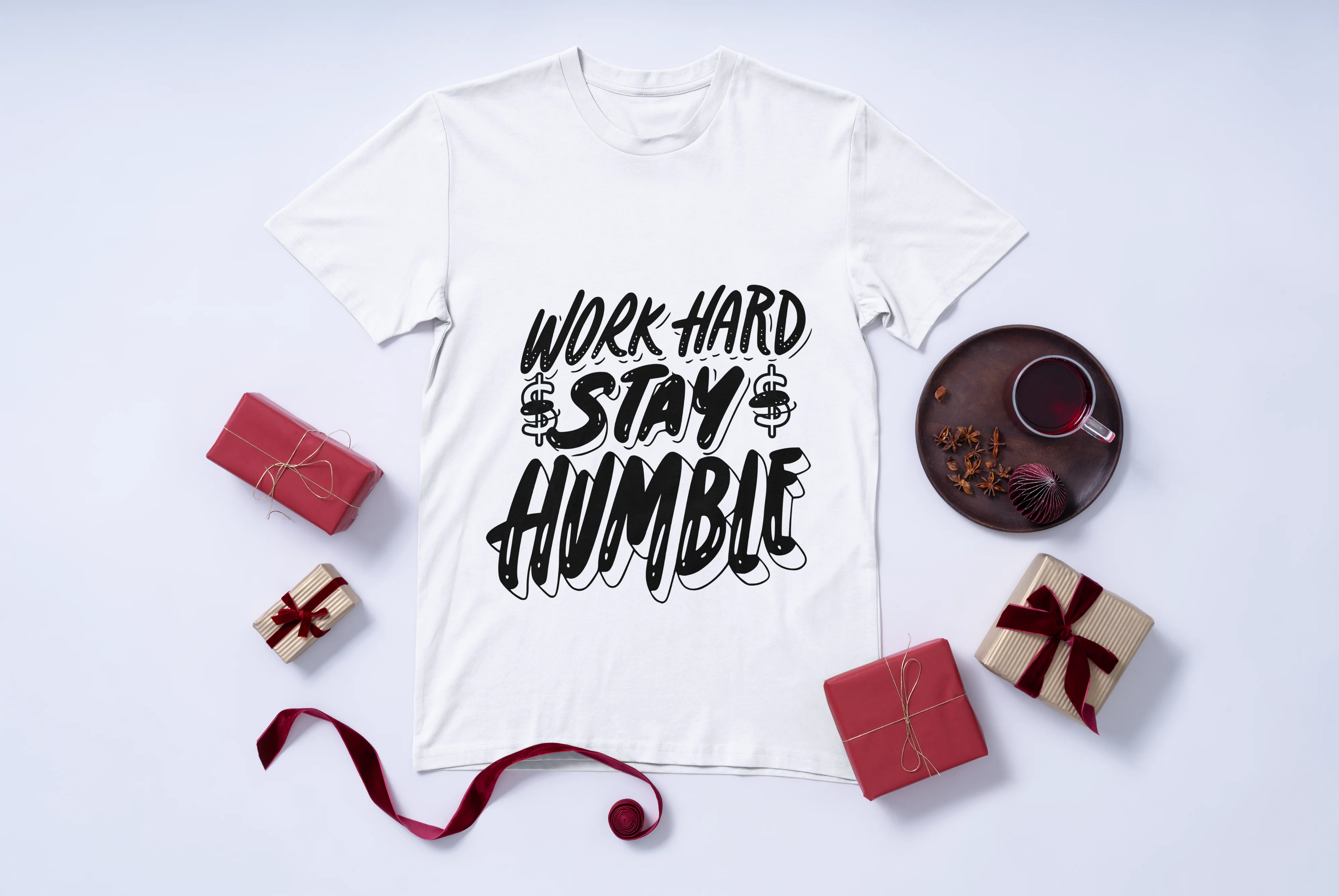 White t-shirt with 'Work Hard Stay Humble' text on a white background with decorative items.