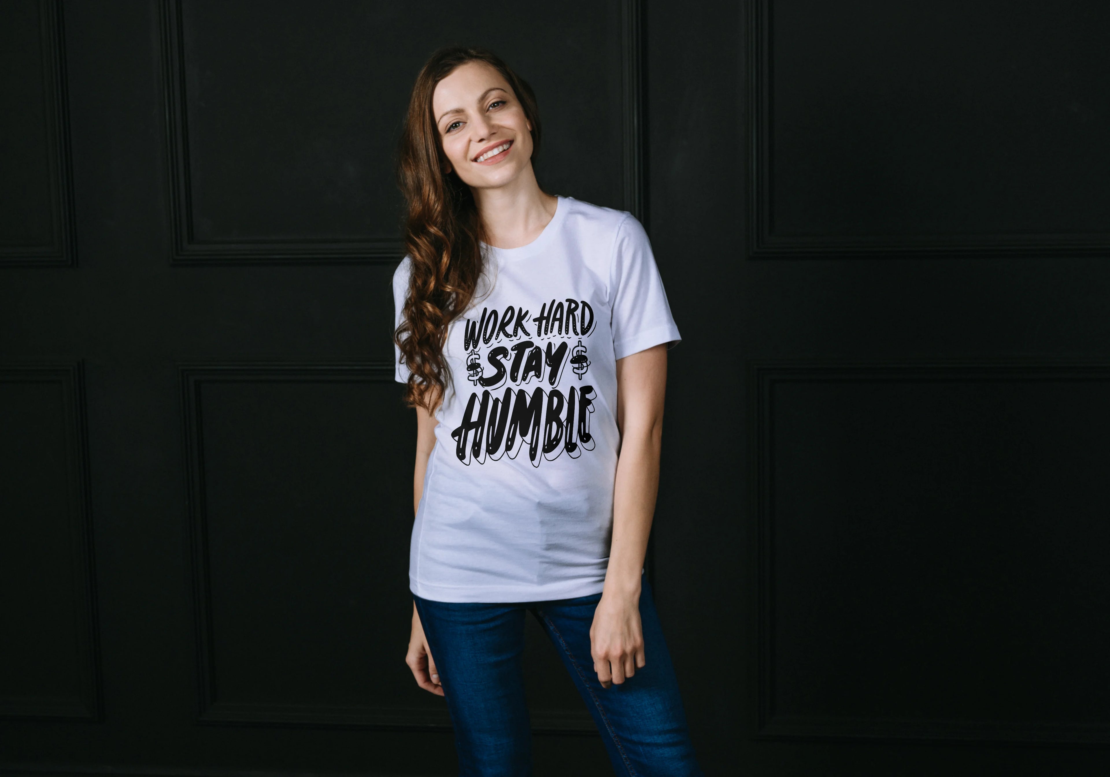 Woman wearing a white t-shirt with 'Work Hard Stay Humble' text against a dark background